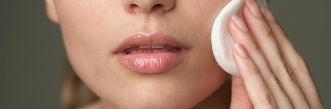 A young woman with a radiant complexion using a cotton pad on her face, demonstrating how to get clear skin naturally